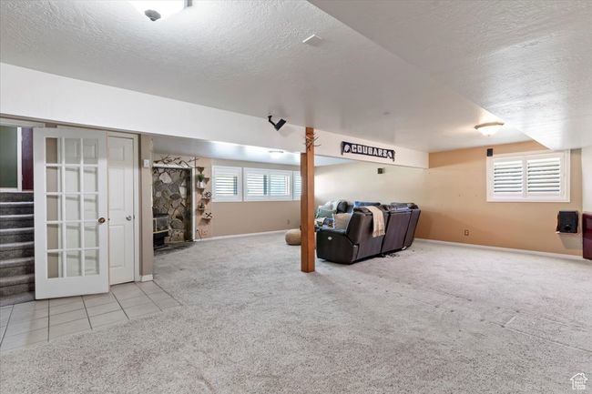 Carpeted living area with a textured ceiling, stairway, baseboards, and tile patterned flooring | Image 15