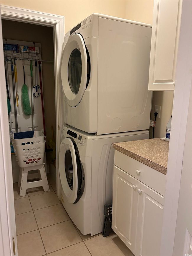 Washroom featuring laundry area, light tile patterned floors, and stacked washer / dryer | Image 13