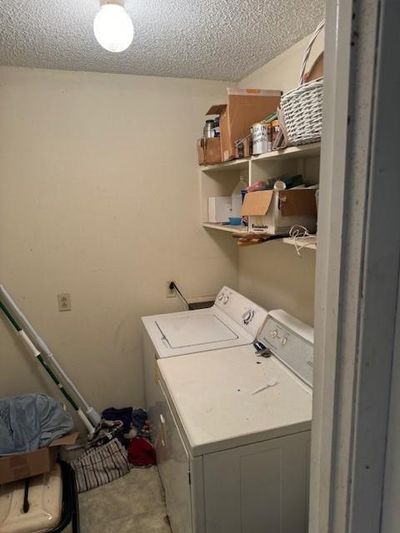 Laundry room featuring washing machine and dryer and a textured ceiling | Image 3