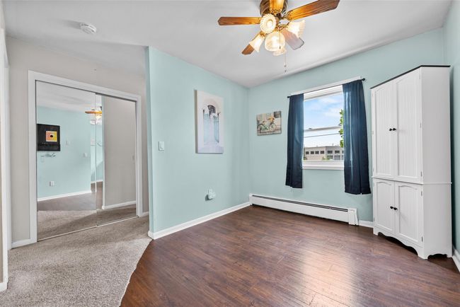Unfurnished bedroom with baseboard heating, wood finished floors, and a ceiling fan | Image 11