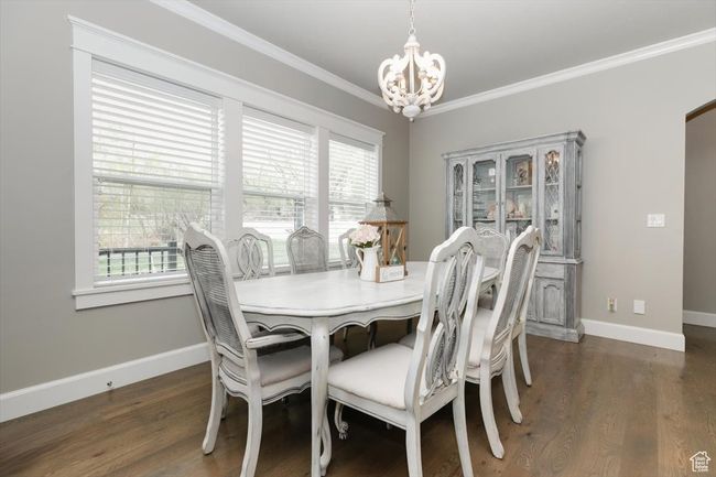 Dining area with ornamental molding, a notable chandelier, wood finished floors, and a healthy amount of sunlight | Image 34