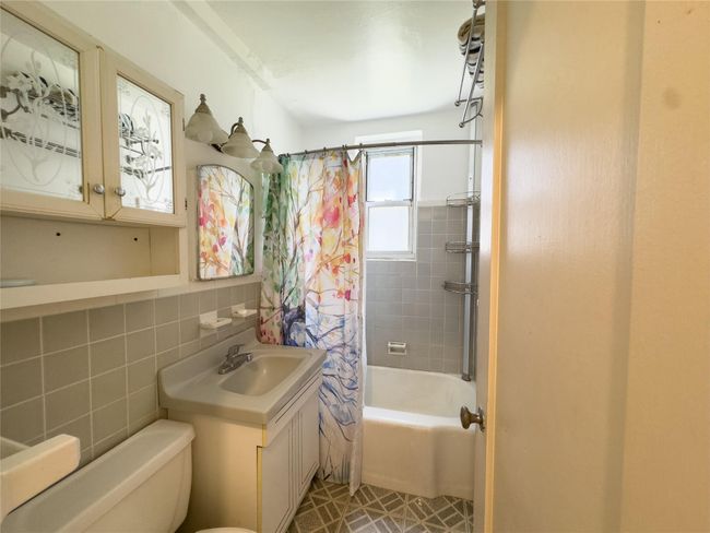 Full bath featuring shower / bath combo, tile walls, and vanity | Image 5