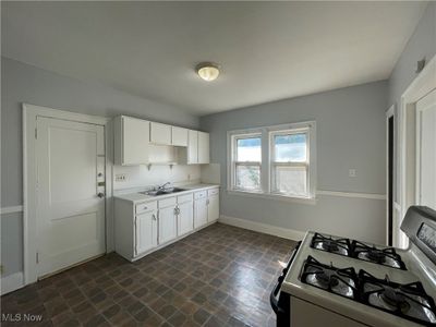 Kitchen with white cabinets, sink, and gas range | Image 3