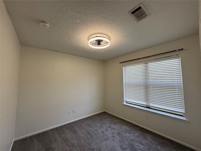 Spare room featuring a textured ceiling, dark carpet, baseboards, and a smoke detector | Image 16