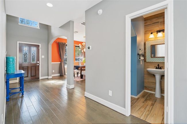 This inviting home features a bright entryway with wood flooring, leading to a colorful dining area. A stylish powder room is conveniently located near the entrance. | Image 22