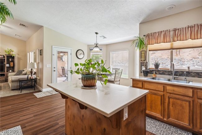 Kitchen featuring a sink, dark wood finished floors, light countertops, brown cabinetry, and a textured ceiling | Image 16