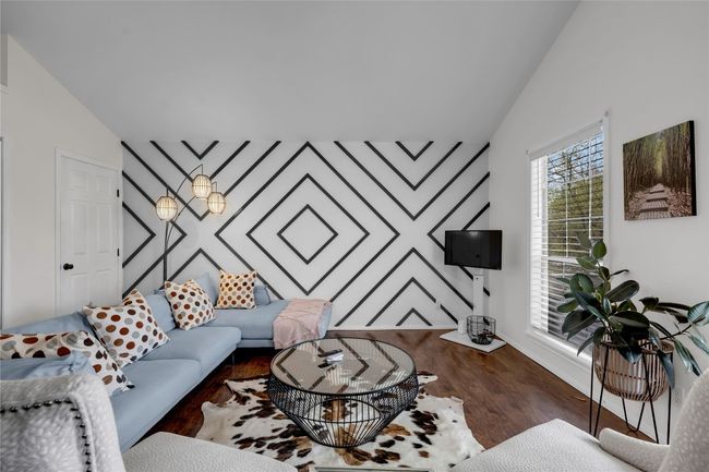 Living room with baseboards, vaulted ceiling, wood finished floors, and an accent wall | Image 24