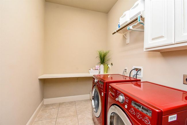 The laundry room has a folding counter and cabinets! | Image 30
