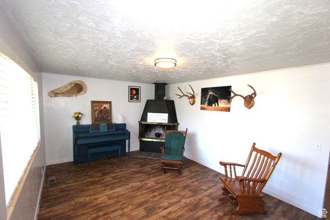Sitting room with wood finished floors and a textured ceiling | Image 8