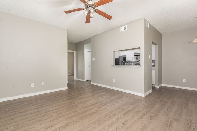 Unfurnished living room with ceiling fan, wood finished floors, a textured ceiling, and baseboards | Image 8