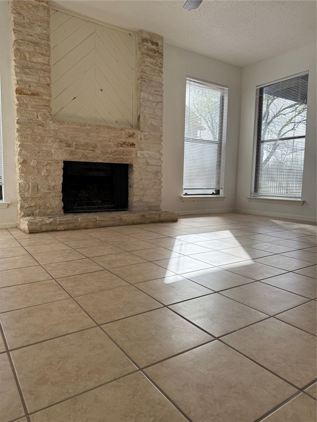 Unfurnished living room featuring tile patterned floors, a fireplace, and a textured ceiling | Image 7