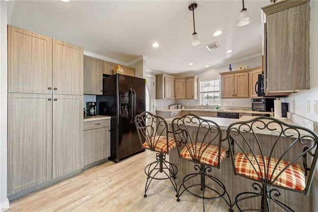Kitchen featuring black appliances, light wood finished floors, visible vents, a peninsula, and crown molding | Image 10