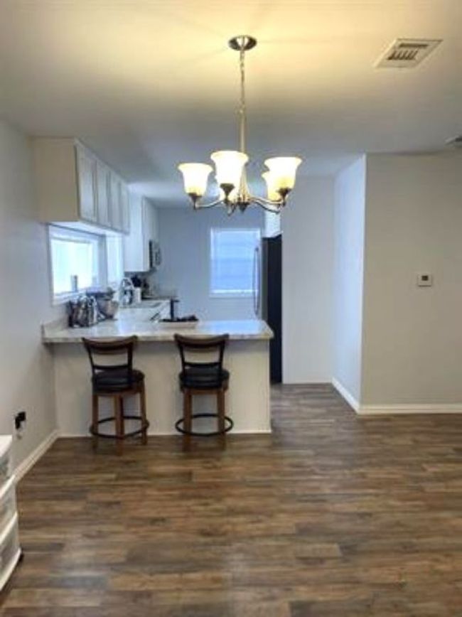 Kitchen featuring a notable chandelier, a peninsula, visible vents, and dark wood-style floors | Image 6