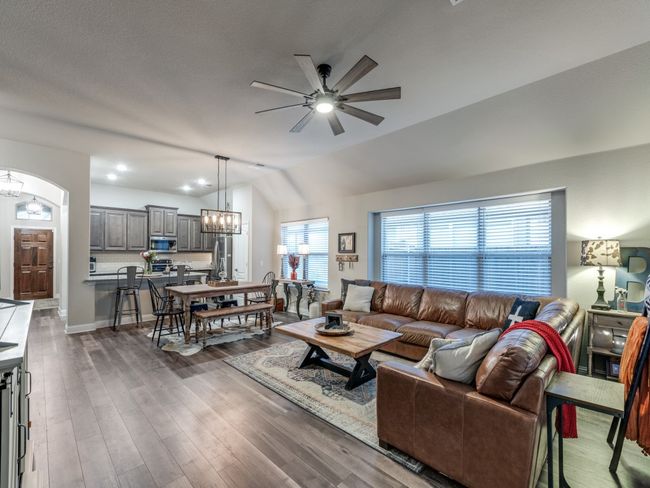 Living room with vaulted ceiling, dark hardwood / wood-style floors, and ceiling fan with notable chandelier | Image 4