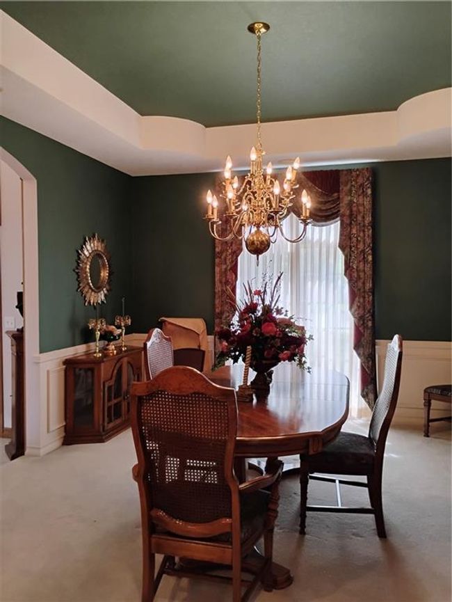Carpeted dining space featuring wainscoting, arched walkways, and a notable chandelier | Image 17