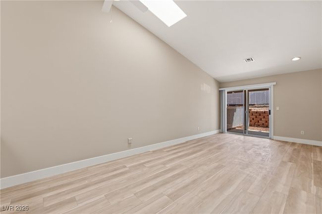 Empty room with a skylight, light wood-style floors, high vaulted ceiling, and recessed lighting | Image 19