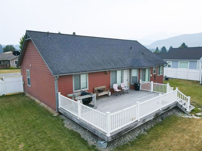 Rear view of house featuring roof with shingles, a yard, a deck with mountain view, and fence | Image 26