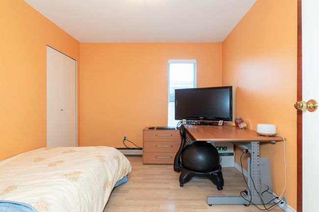 Bedroom with light wood-style floors, a baseboard heating unit, a closet, and a desk | Image 26