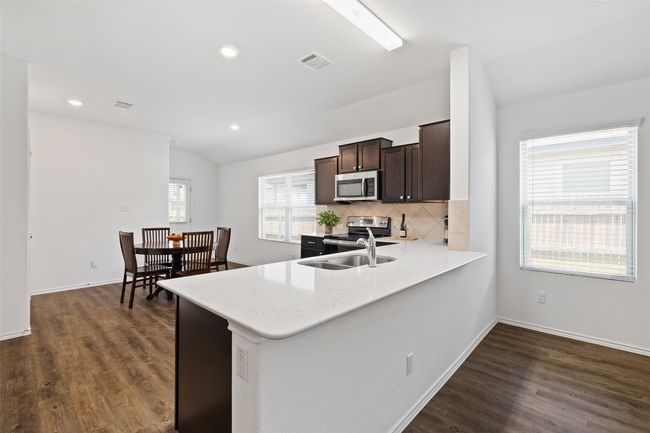 Kitchen with stainless steel appliances, dark brown cabinetry, backsplash, dark wood finished floors, and vaulted ceiling | Image 9
