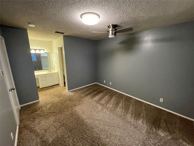 Carpeted spare room featuring built in desk, ceiling fan, and a textured ceiling | Image 13