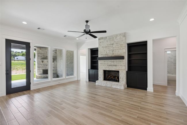 Unfurnished living room featuring crown molding, ceiling fan, a fireplace, and light hardwood / wood-style floors | Image 7