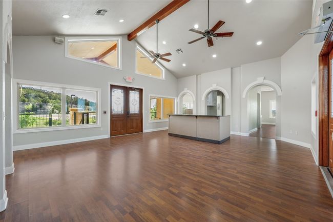 Unfurnished living room with arched walkways, visible vents, high vaulted ceiling, and ceiling fan | Image 6