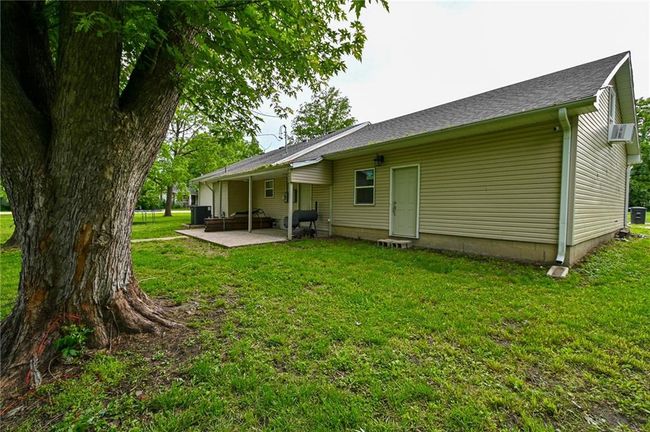 Rear view of house with a patio, a lawn, cooling unit, and a shingled roof | Image 37