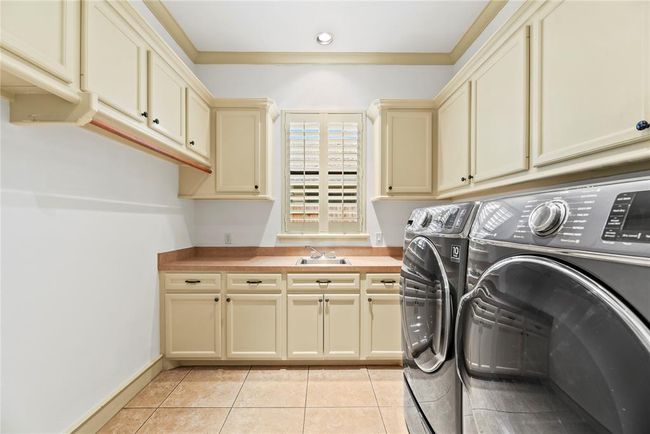 Laundry room with ample cabinetry, sink & plantation shutters | Image 27