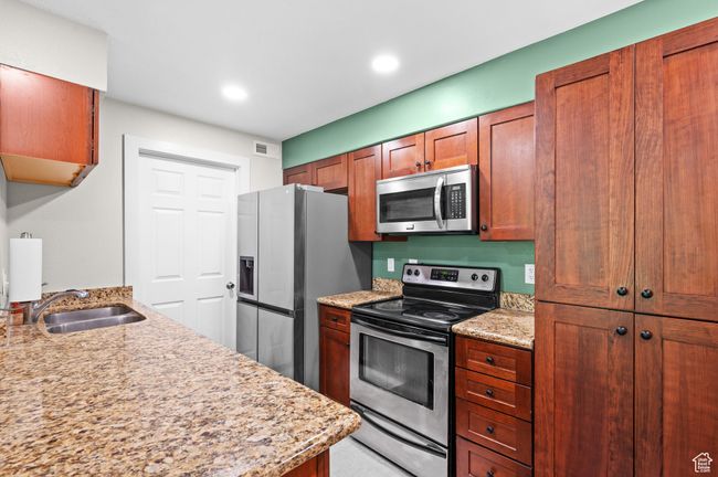 Kitchen featuring stainless steel appliances, light stone counters, brown cabinets, and recessed lighting | Image 7