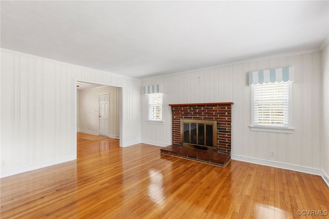 Unfurnished living room featuring a fireplace, light wood-style floors, ornamental molding, and baseboards | Image 9