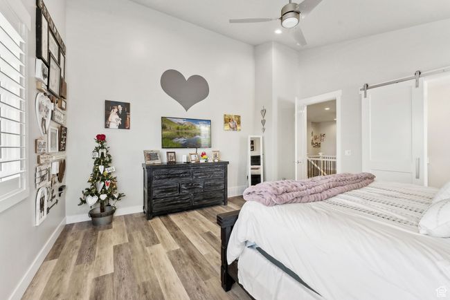 Bedroom with a barn door, light wood-style floors, baseboards, recessed lighting, and a high ceiling | Image 13