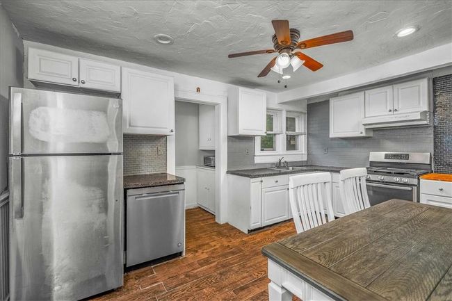 Unit # 70 Kitchen featuring tasteful backsplash, appliances with stainless steel finishes, ceiling fan, white cabinets, and dark wood-type flooring | Image 28