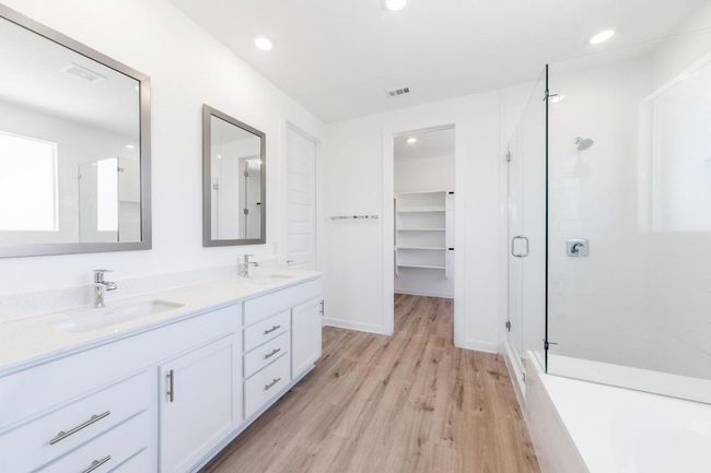 Full bath featuring a stall shower, double vanity, wood finished floors, recessed lighting, and a spacious closet | Image 12