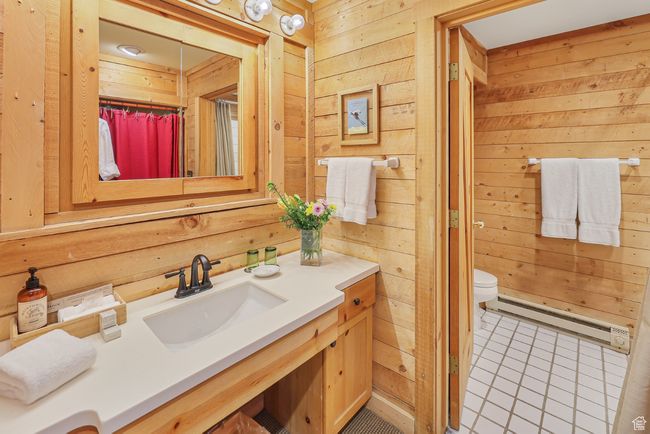 Full bathroom with wooden walls, baseboard heating, vanity, toilet, and tile patterned flooring | Image 50