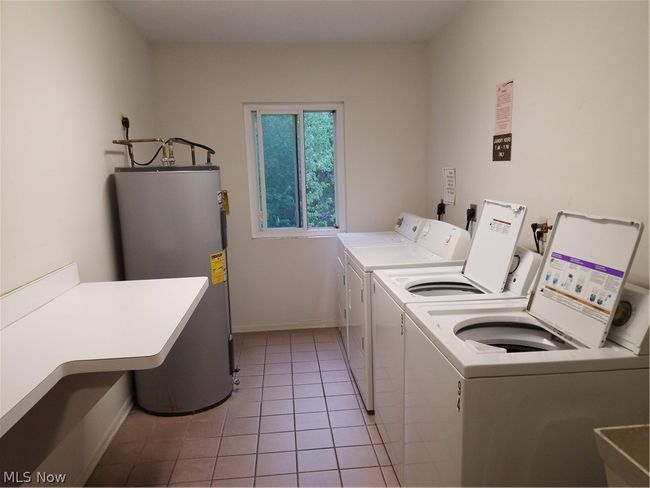 Laundry area featuring water heater, independent washer and dryer, electric dryer hookup, and light tile floors | Image 32