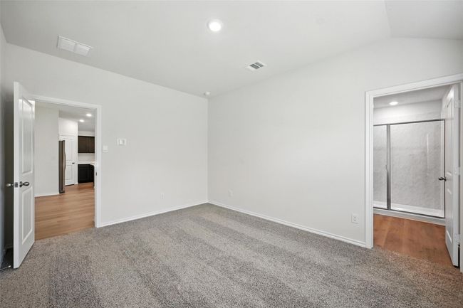 Unfurnished bedroom featuring carpet floors, stainless steel refrigerator, recessed lighting, and lofted ceiling | Image 15
