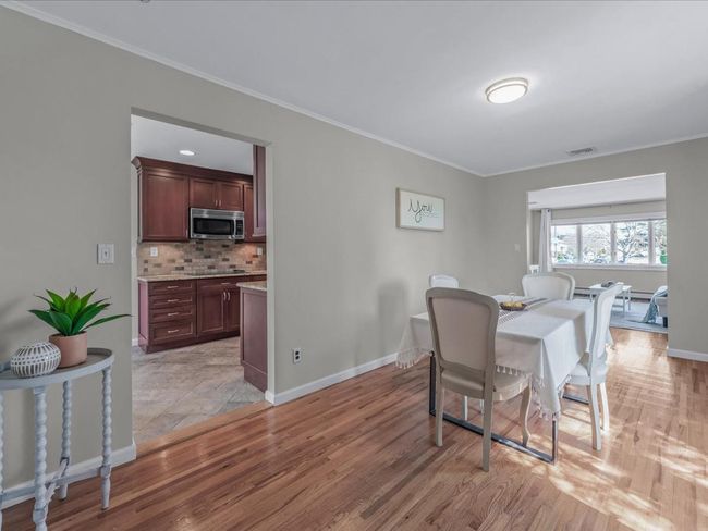 Dining space with crown molding, baseboards, light wood finished floors, and visible vents | Image 7