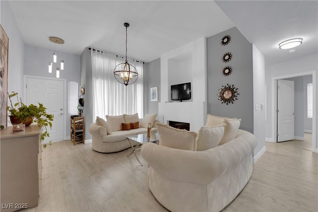 Living room with light wood-type flooring, a fireplace, and a chandelier | Image 6