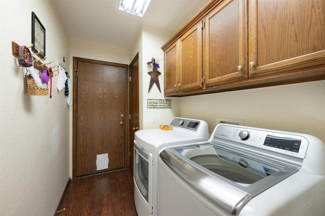 Laundry room featuring washing machine and clothes dryer, cabinet space, and dark wood-style floors | Image 22