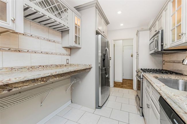 Kitchen featuring stainless steel appliances, radiator heating unit, backsplash, recessed lighting, and light stone countertops | Image 19