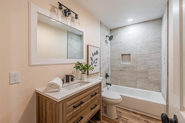 Bathroom with bathing tub / shower combination, wood finished floors, vanity, and toilet | Image 16