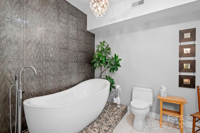 Spa bathroom in lower level with huge soaking tub, toiet area and not pictured a custom vanity area with custom raw edge wood counter. | Image 33