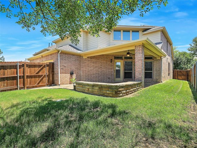 Back of property with ceiling fan, a fenced backyard, a gate, brick siding, and a patio | Image 36