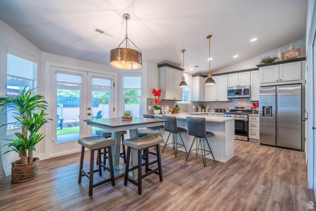 Kitchen with vaulted ceiling, a breakfast bar, kitchen peninsula, hanging light fixtures, and stainless steel appliances | Image 29