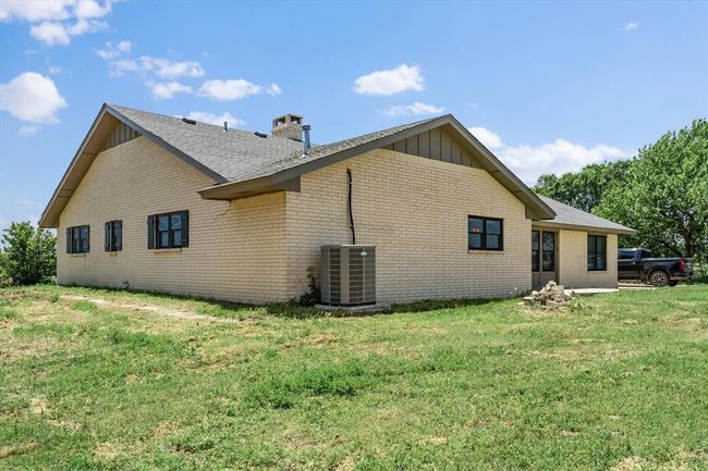 Rear view of house with board and batten siding, brick siding, central AC unit, a chimney, and a lawn | Image 37