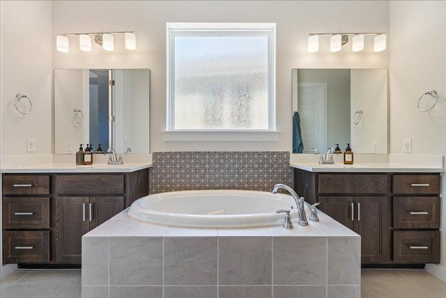 Bathroom featuring a garden tub, a sink, two vanities, and tile patterned flooring | Image 23