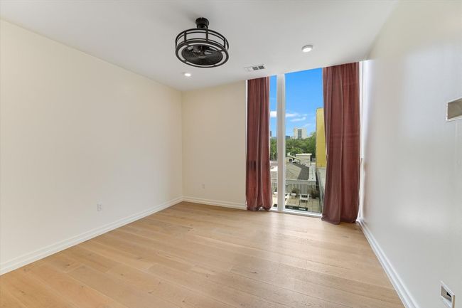 Empty room with expansive windows, baseboards, visible vents, and light wood-type flooring | Image 7