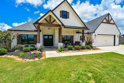 This enchanting view of the front of the home is nothing short of magazine worthy with manicured walkway, lush planting beds lined with gorgeous stone; and an amazing covered front porch and double door main entrance, welcomes you in! | Image 2