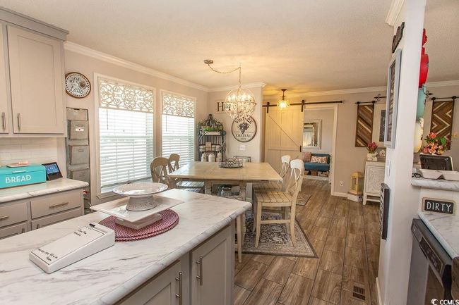 Kitchen featuring crown molding, gray cabinets, a barn door, and dark wood-type flooring | Image 11