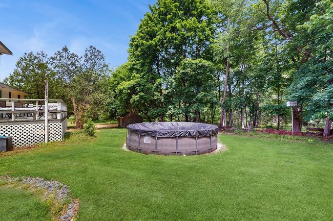 View of lush green lawn featuring a pool and a deck | Image 41
